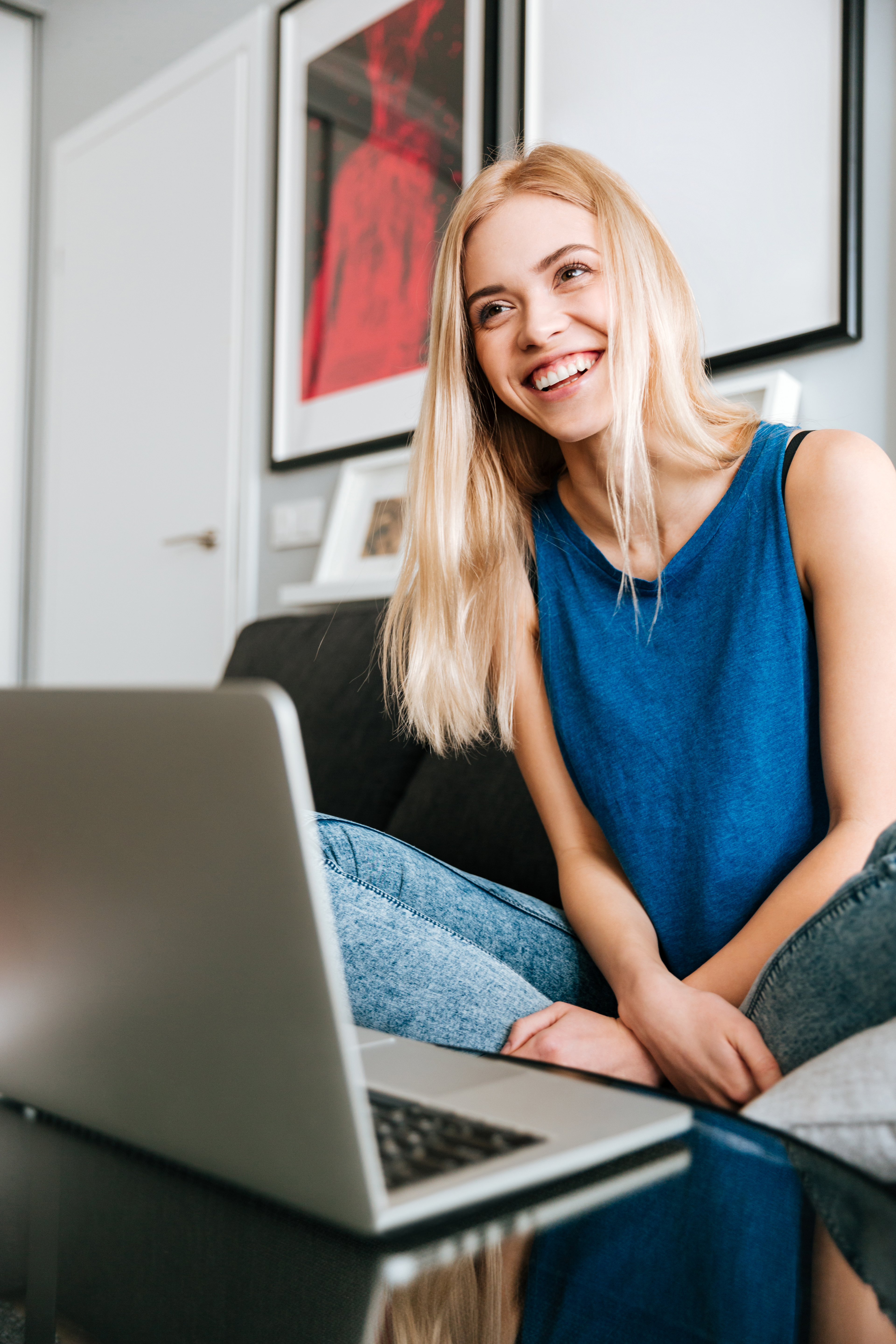 Cheerful woman sitting and using laptop at home